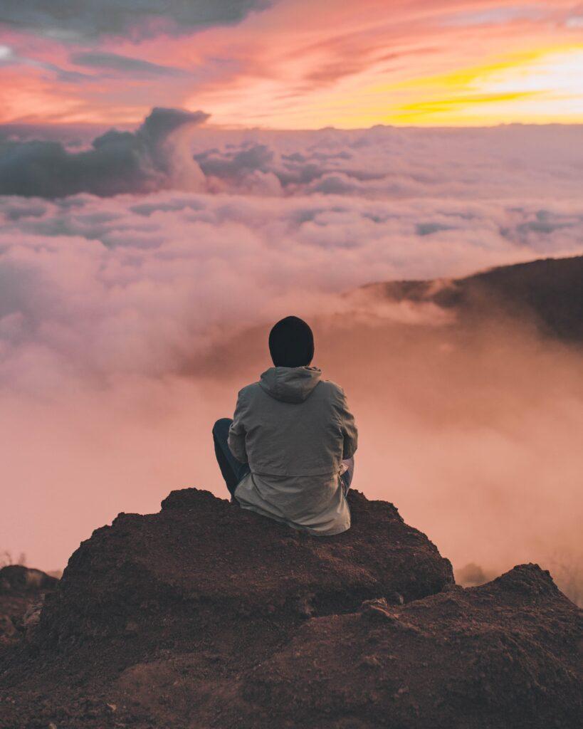 man sitting alone, man spending time alone, man on top of a mountain, man being courageous, courage